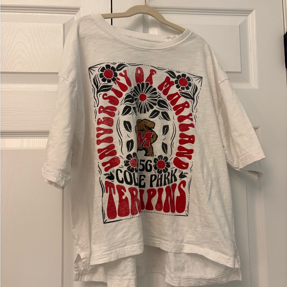 University of Maryland Women’s White and Red T-Shirt. Loose fit cuts to the hip